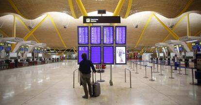 Un home mira les pantalles de facturació de Madrid-Barajas.