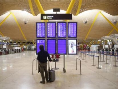 Un home mira les pantalles de facturació de Madrid-Barajas.