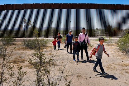 Una familia de migrantes guatemaltecos camina junto al muro fronterizo entre México y Estados Unidos, cerca de la población de Lukeville (EE UU), en agosto de 2023.