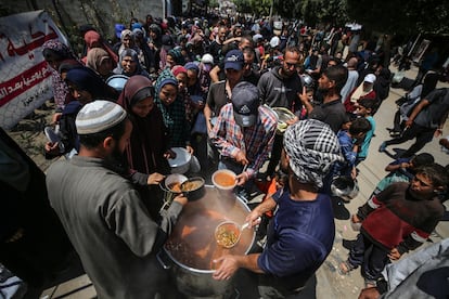 Displaced Palestinians receive cooked food rations at a donation point in Deir al-Balah, central Gaza Strip, April 16, 2024.