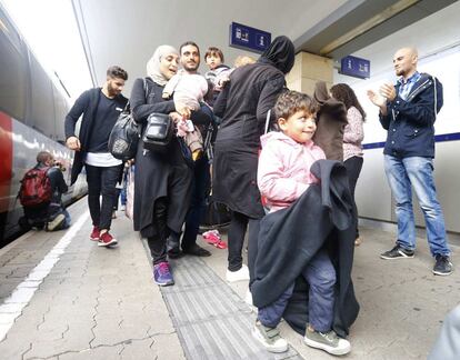 Un joven aplaude a una familia de refugiados a su llegada a una estación de Viena.