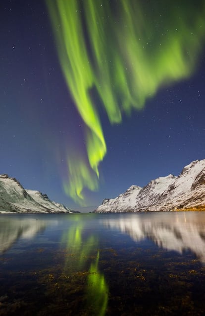 Las cristalinas aguas del Ersfjord hacen de espejo para la aurora boreal.