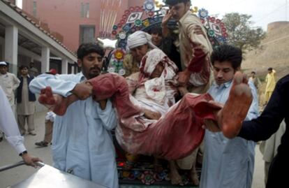 Varias personas trasladan a uno de los heridos en el atentado suicida en la mezquita de Pakistán.