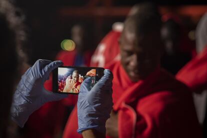 Una voluntaria de Cruz Roja hace una foto a un inmigrante con el móvil de este en el barco de Salvamento Marítimo Luz de Mar.