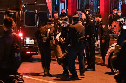 Un hombre es arrestado durante las protestas en Shanghái, este domingo. Varias personas han acudido con flores al lugar, que los agentes no les han dejado depositar en el suelo.