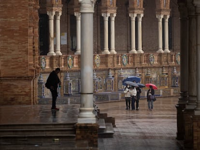 Varias personas se refugian de la lluvia, este viernes en Sevilla.