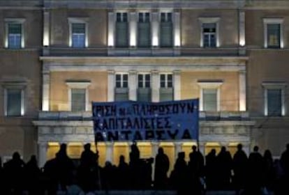 Manifestantes sostienen una pancarta en la protesta que ha habido en el exterior del Parlamento griego en la jornada en que se ha aprobado el presupuesto para 2013.