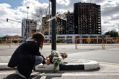 Una mujer deja un peluche, este sábado, junto a varios ramos de flores en recuerdo a las víctimas del incendio de un edificio en el barrio de Campanar de València que se ha cobrado la vida de al menos 10 personas.