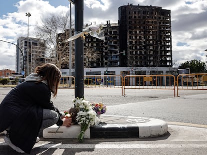Una mujer deja un peluche, este sábado, junto a varios ramos de flores en recuerdo a las víctimas del incendio de un edificio en el barrio de Campanar de València que se ha cobrado la vida de al menos 10 personas.
