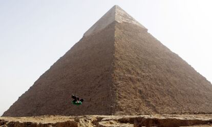 Un joven practica un salto delante de la pirámide de Keops, la mayor de las grandes pirámides de Giza, en las afueras de El Cairo.