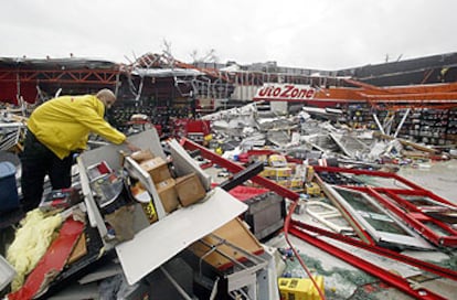 Un empleado de un gran almacén de repuestos de coche limpia el recinto, medio derruido tras el paso del huracán <i>Charley.</i>