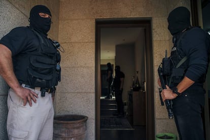 Dos policías custodian la entrada de la vivienda de Pontevedra mientras sus compañeros registran el interior.