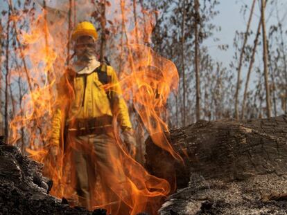 Bombeiro atrás de chamas durante o combate aos incêndios na floresta amazônica, próximo de Porto Velho.