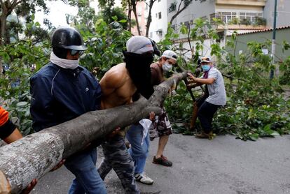 Partidarios de la oposición arrastran un árbol cortado para utilizarlo como barricada.