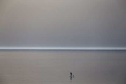 Un surfista rema sobre su tabla por un Mediterráneo en calma, cerca de Beit Yanai, Israel.