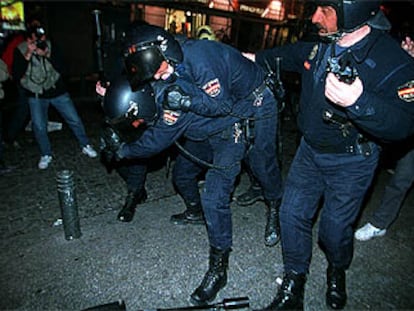 Un agente traslada a un compañero herido en los violentos incidentes de la noche del sábado en Madrid.