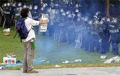 Un joven, ayer en Miami con un cartel en el que se lee: "El ALCA daña a los trabajadores y al medio ambiente".