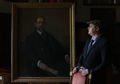El pintor Alejandro Cabeza junto al último retrato que ha pintado, el del geólogo Lucas Mallada, en el Museo Geominero de Madrid.