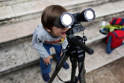 Un niño contempla el eclipse en Lisboa a través unos prismáticos a los que se ha incorporado un filtro casero de rayos X.