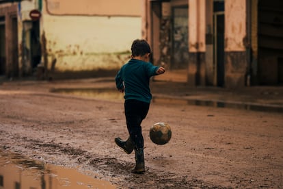 Aunque el aspecto de las calles de Paiporta había mejorado, el lodo aún estaba presente el 14 de noviembre. En la imagen, un niño con botas de goma juega con un balón en una calle parcialmente recuperada, reflejando un atisbo de normalidad en uno de los primeros días en los que la localidad comienza a levantarse tras la catástrofe.