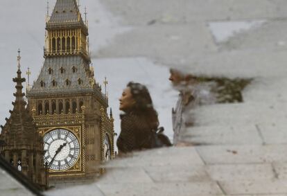 Una mujer se refleja junto al Big Ben en un charco de agua cerca del Parlamento de Londres.