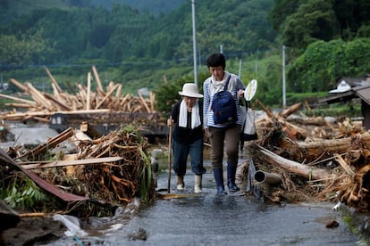 El número de fallecidos por las lluvias torrenciales que azotaron esta semana la isla nipona de Kyushu (suroeste) se ha elevado hoy a 16. En la foto, residentes de una zona muy afectada por las inundaciones abandonan sus hogares, hoy en Toho (Japón).