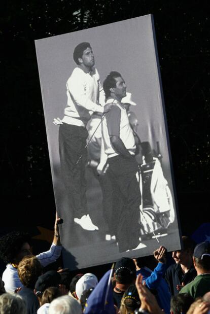 Los aficionados llevan el póster de Olazábal y Ballesteros que los jugadores europeos tuvieron en su vestuario en la pasada Ryder.