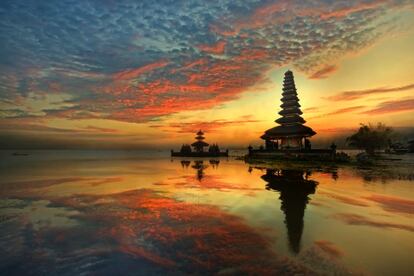 En la gran mayoría de los países, las entradas a los lugares más turísticos son considerablemente caras si lo comparamos con el nivel de vida del lugar. En el caso de Indonesia, donde el salario medio son 2.069.306 rupias (unos 135 euros), muchos de sus templos pueden visitarse por aproximadamente un euro, especialmente en la turística isla de Bali. <br> En la fotografía, una puesta de sol en el templo Ulun Danu Bratan, en la isla de Bali.