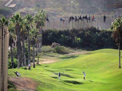 Esta foto ha dado la vuelta al mundo. El campo de golf de Melilla y al fondo la valla. Representa la diferencia norte-sur, la desigualdad, dos mundos tan diferentes pero reales y cercanos. El no querer ver lo que está pasando a nuestro lado. La travesía de las personas que se encuentran tras la valla comienza cruzando el desierto, etapa que muchas personas no logran superar. Aquéllas que lo consiguen continúan un largo viaje durante el que sufren robos, violaciones y todo tipo de maltratos por parte de las mafias. Para poder continuar hasta Marruecos se ven forzadas a trabajar en lo que pueden, con salarios muy bajos, con el fin de seguir avanzando.  Solo de enero a junio de 2016, 3.120 personas la perdieron tratando alcanzar Europa, casi el mismo número que en todo 2015.