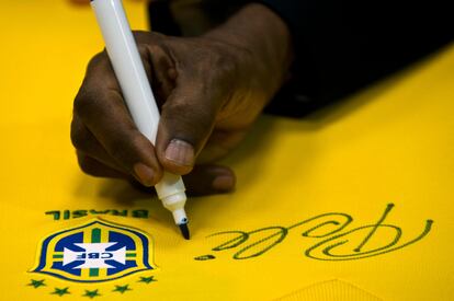 In this file photo taken on June 10, 2013, Brazilian football legend Edson Arantes do Nascimento, known as Pele, signs a Brazilian national team shirt.