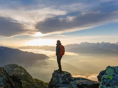 Un viajero contemplando su vida desde lo alto de una montaña.