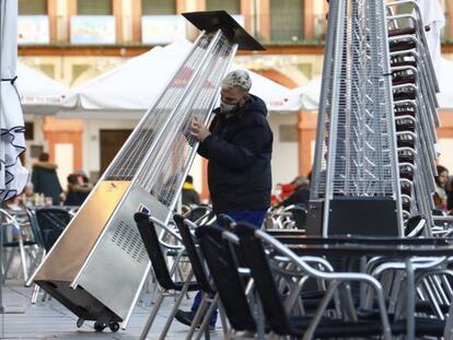 Un trabajador recoge el mobiliario de la terraza de un restaurante en el centro de Córdoba hoy lunes cuando han entrado en vigor las nuevas restricciones en Andalucía