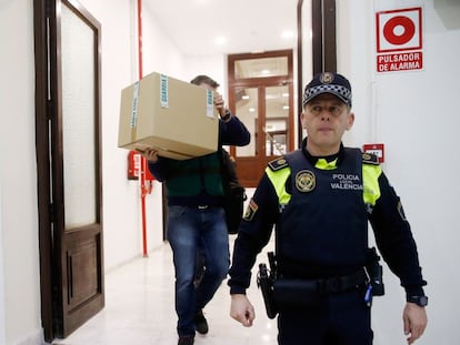 Un agente lleva una caja de las oficinas del PP en Valencia el martes.