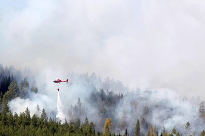 Un helicóptero de los servicios de emergencia trata de extinguir un incendio en Karbole (Suiza).