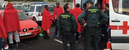 Agentes de la Guardia Civil y de Cruz Roja atienden a un grupo de inmigrantes que ha desembarcado este sábado en Ceuta.
