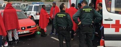 Agentes de la Guardia Civil y de Cruz Roja atienden a un grupo de inmigrantes que ha desembarcado este s&aacute;bado en Ceuta. 