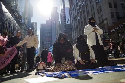 Varias mujeres rezan mientras dos hombres miran una bandera durante una manifestación a favor de los musulmanes americanos, y como protesta por las políticas de inmigración del presidente Donald Trump en Times Square, Nueva York (EE UU).