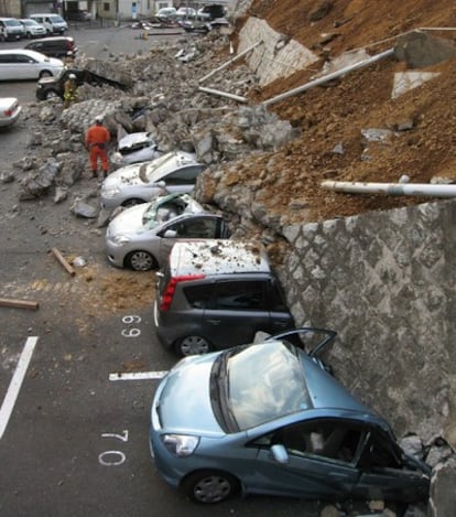 Coches aplastados por un muro derrumbado en un aparcamiento en la ciudad de Mito, en la provincia de Ibaraki, después del terremoto que sacudió Japón hoy viernes