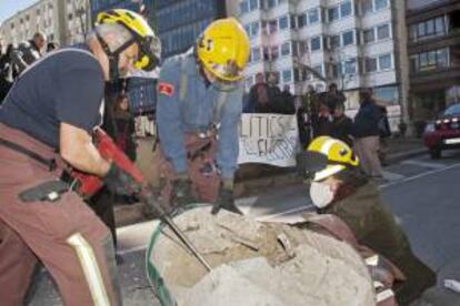 Efectivos de los Bomberos de la Generalitat proceden a liberar a las dos activistas.