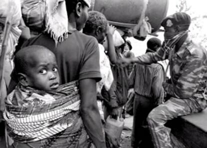 Un soldado zaireño, protegido con un pañuelo, cachea en la frontera a los refugiados procedentes de Ruanda. 15/07/1994