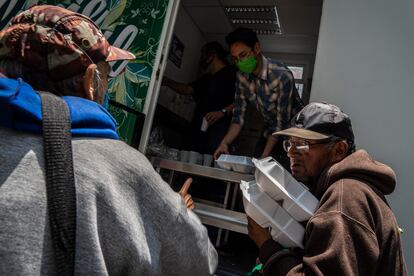 Varios hombres reciben comida de forma gratuita en el Parque de los Venados de la Ciudad de México.