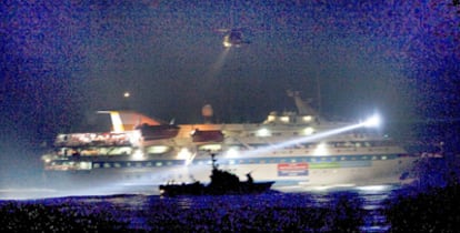 La silueta de una patrullera israelí se recorta sobre uno de los barcos de la <b>flotilla</b> durante el asalto.