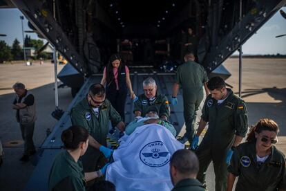 Los cooperantes bajan del avión a un paciente en su llegada a España.