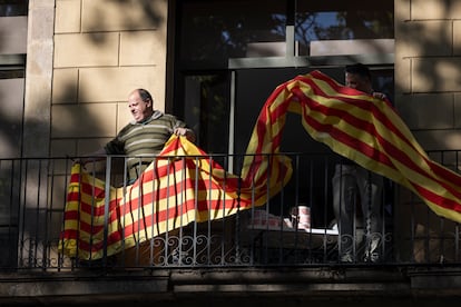 Un vecino de las Ramblas coloca una bandera de Cataluña en su balcón.