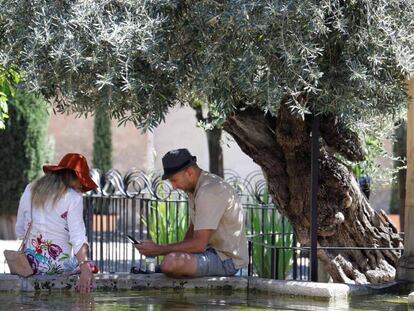 Dos personas sentadas en una fuente en el Patio de los Naranjos de la Mezquita de Córdoba.
