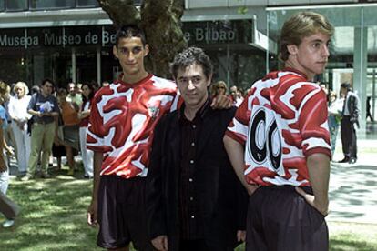 El pintor Darío Urzay posa junto a dos juveniles del Athletic que lucen la nueva camiseta del equipo.