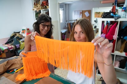 Ángela muestra a cámara una tira con los característicos flecos de seda de Gloriaca, un guiño a su identidad española. De fondo, Gloria, la diseñadora, sostiene el bolso.