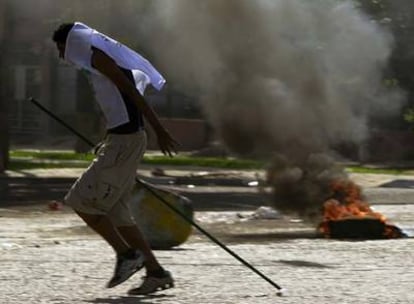 Un huelguista armado con un palo corre entre neumáticos en llamas en las calles de Santa Cruz de la Sierra.