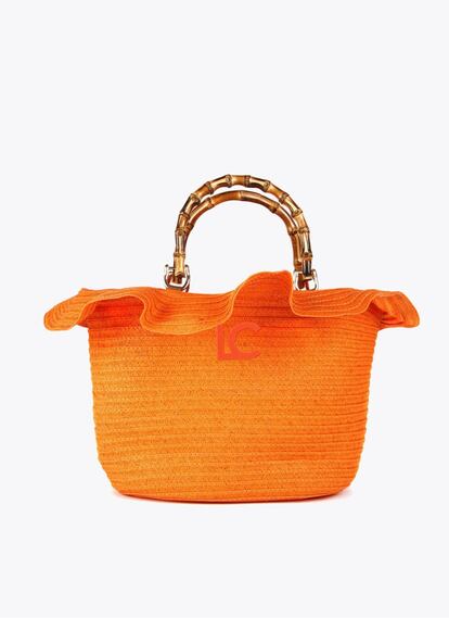 El verano se materializa en este capazo de Lola Casademunt, en naranja intenso, rematado con un volante y el asa con efecto bambú. 69,95 €