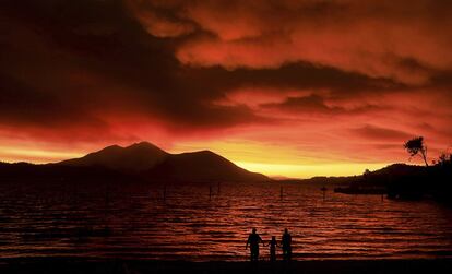 Moradores contemplam o pôr do sol enquanto a fumaça do incêndio eleva-se para o céu em Austin Park Beach, com o Monte Konocti de fundo.